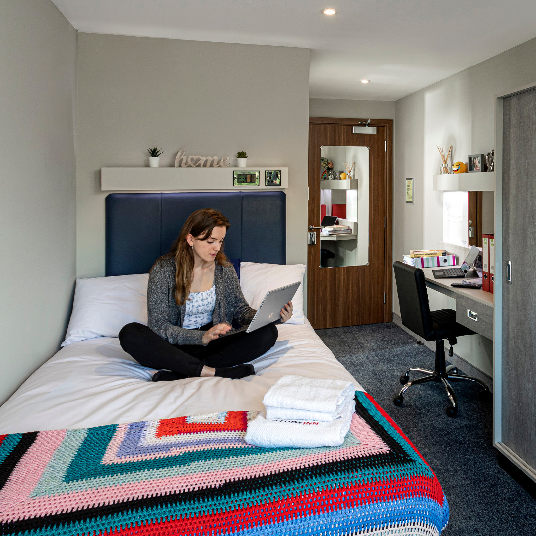 Study Inn resident student on her bedroom bed studying