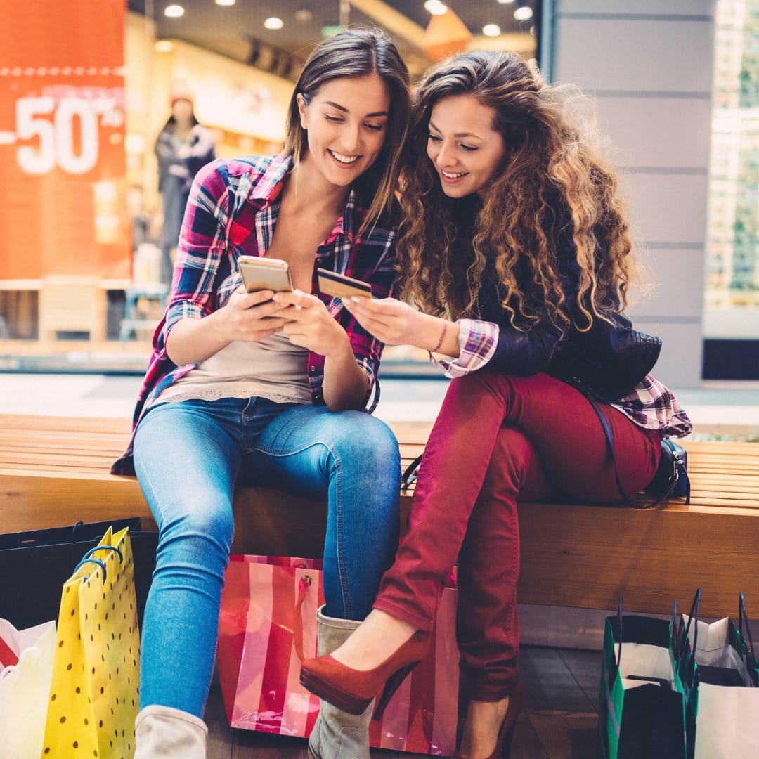 Two university students looking at their phones at Leicester shopping centre
