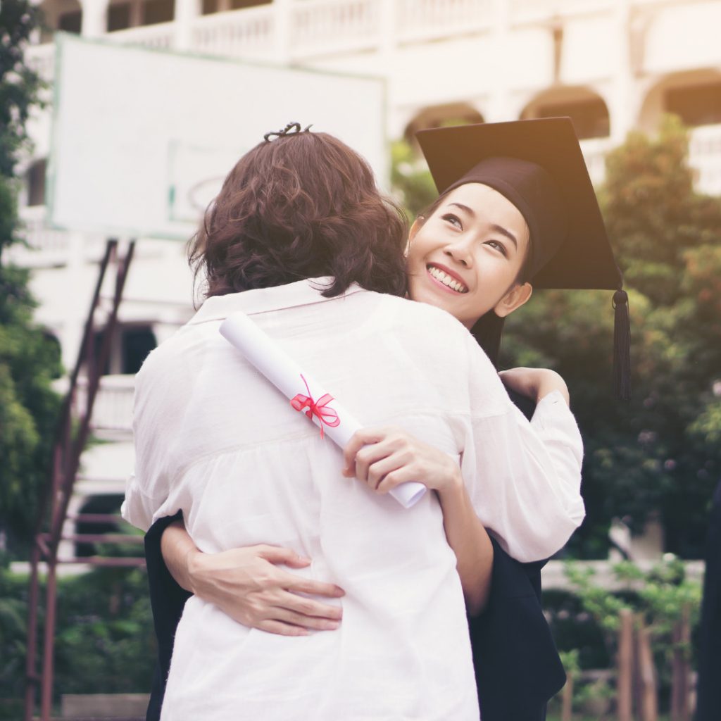 Student hugging a family member holding her graduation certificate on her graduation day