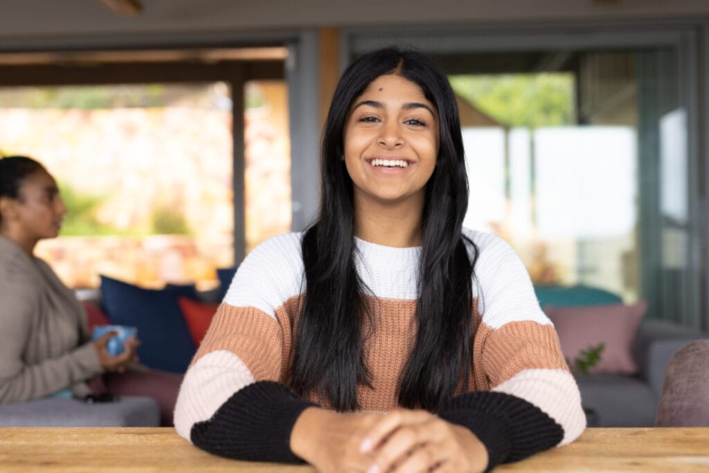 Portrait of happy biracial teenage girl sitting at table