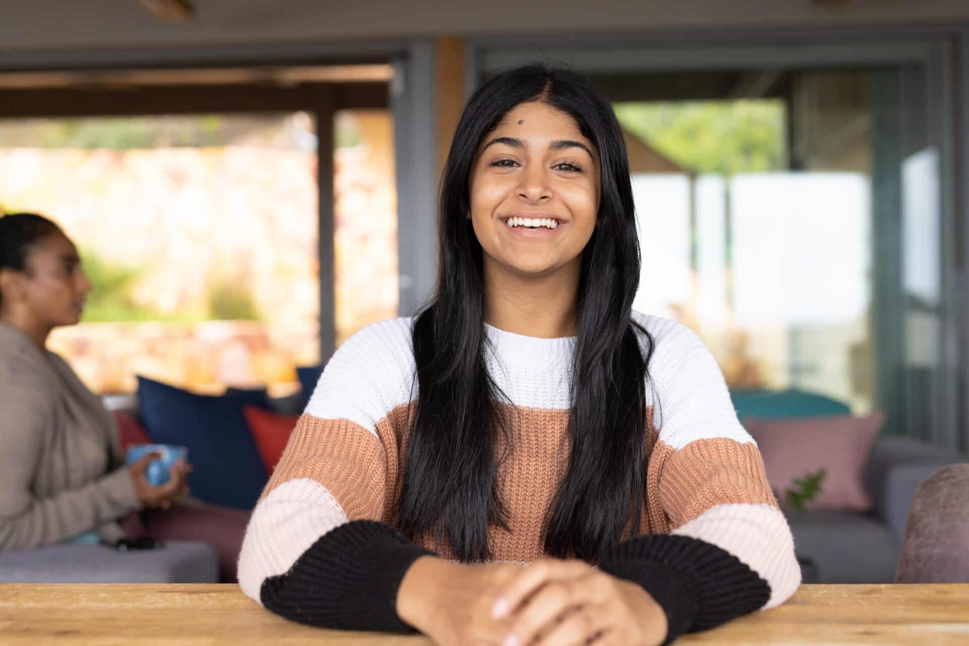 Portrait of happy biracial teenage girl sitting at table