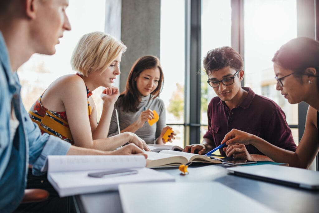 Diverse group of young people sitting at table reading books
