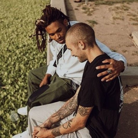 University students talking outdoors, one seems to be supporting the other by putting their arm around them