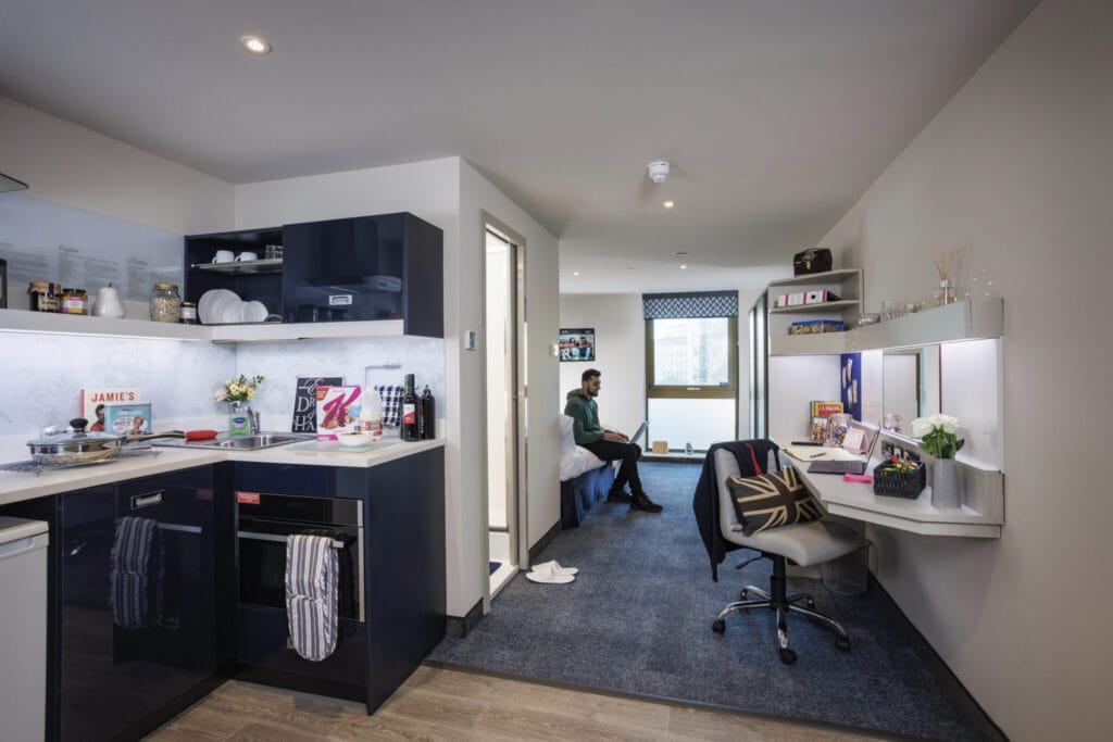 Study Inn Leeds, student accommodation in Leeds. Sapphire studio with student sitting on the bed.