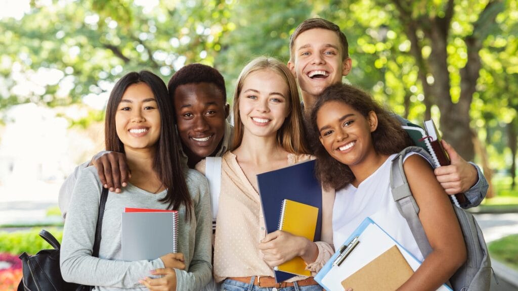 International students in Leeds posing for a photo outdoors on a summer day, holding their books.