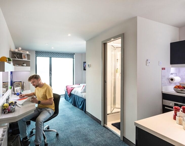 Student reading a book in his studio room at Study Inn.