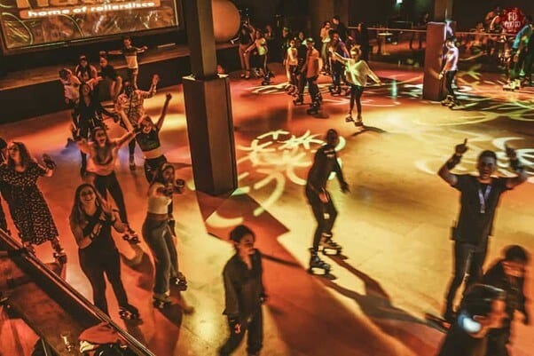 Students enjoying a roller blade party in the dark with neon lights.