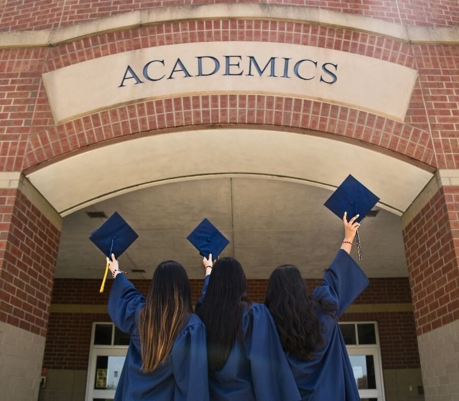 Female university students celebrating their graduation day throwing their graduation hats up in the air.