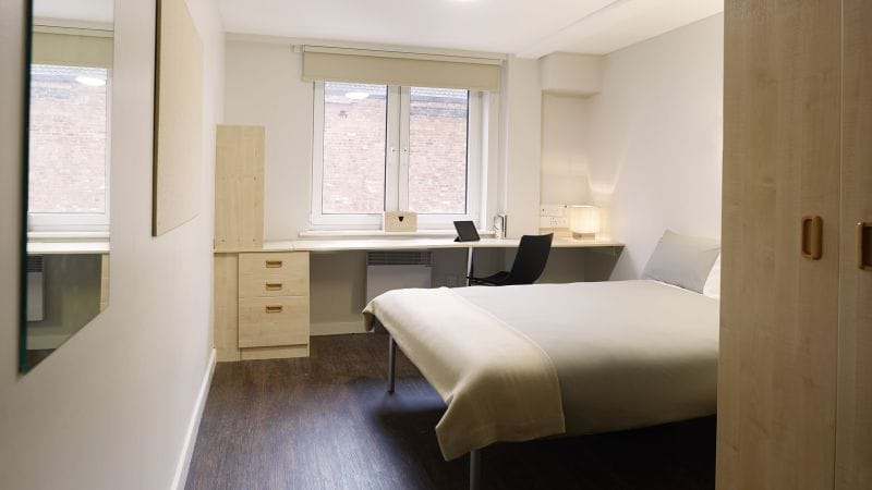 Grosvenor House's Apartment room, with a bed, work desk, chair, laptop and a wardrobe.