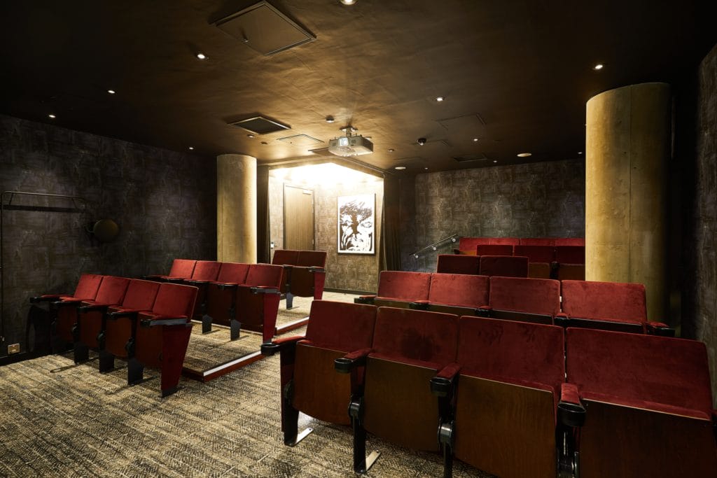 Dark and empty cinema room with red chairs in a student accommodation in Leeds.