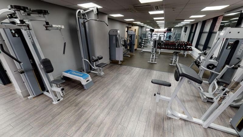 A bright and empty gym with a variety of weights and exercise machines in a student accommodation in Leeds. 