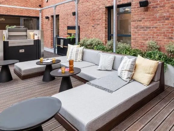 The Aspen outdoor dining area. L shaped sofas, cushions, rugs, small tables and a BBQ.