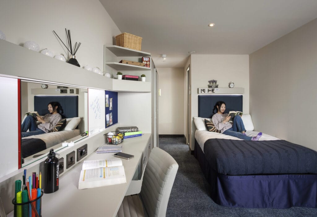 Study Inn Leeds, student accommodation in Leeds. Sapphire apartment with student sitting on bed reading a book.