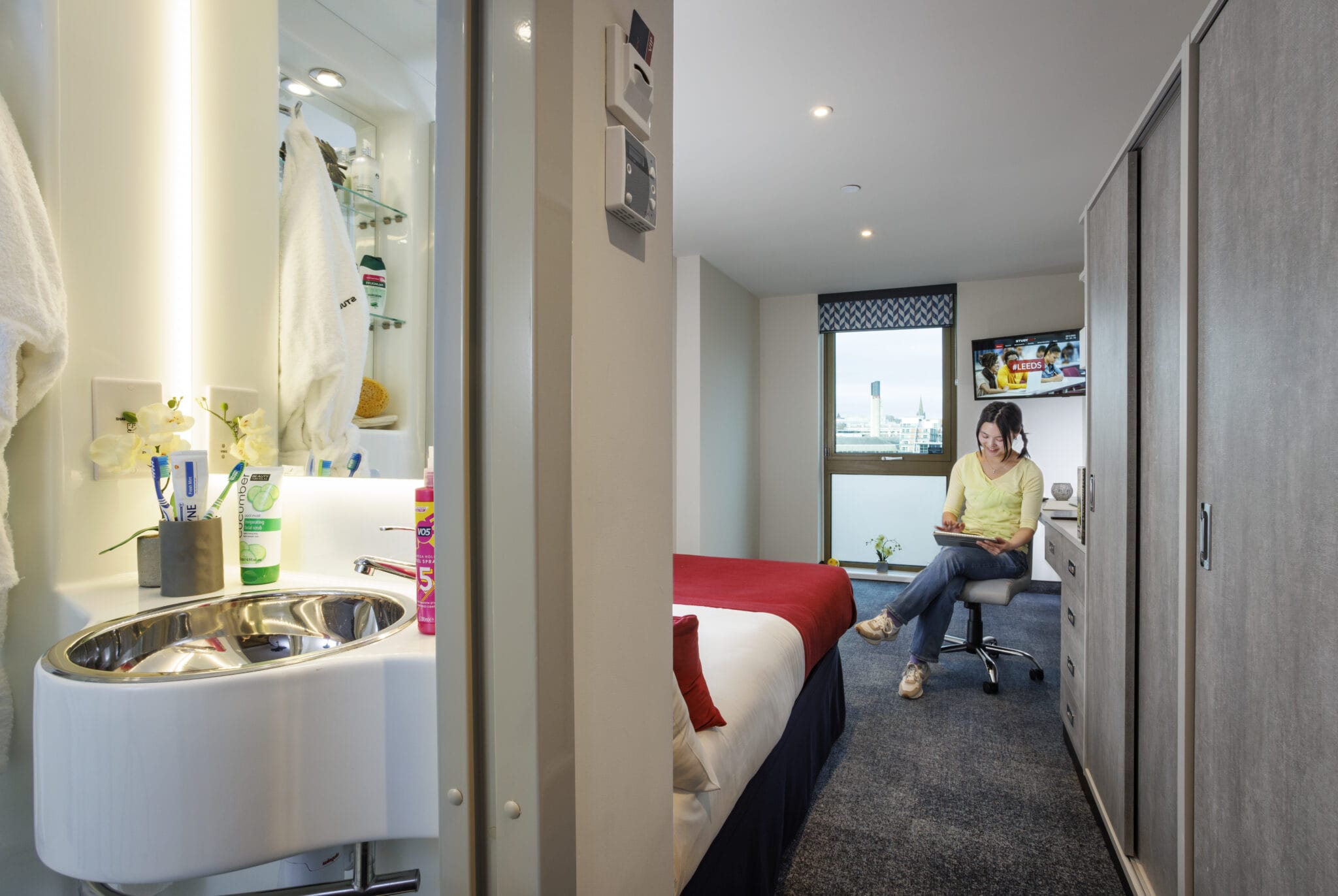 Study Inn Leeds, student accommodation in Leeds. Sapphire Plus apartment with student sitting on chair reading a book.