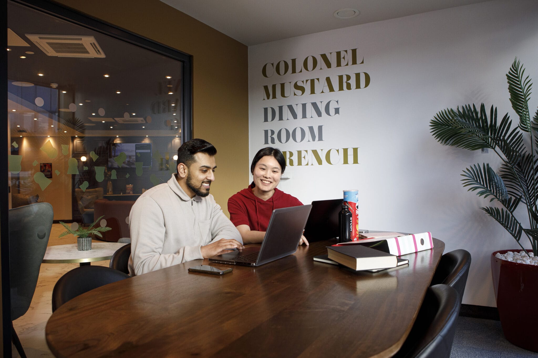 Study Inn Leeds student study rooms, two students working together in the study room. Looking over laptop.