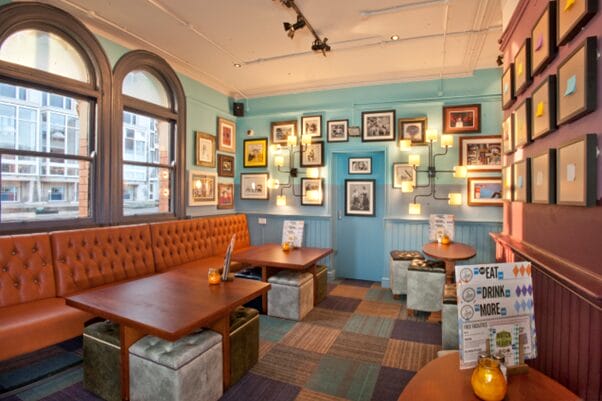 Empty room at Library in Leeds. Brown sofas and tables, pictures on the wall. No customers.