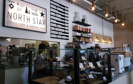 Two baristas working behind the counter at a cafe.