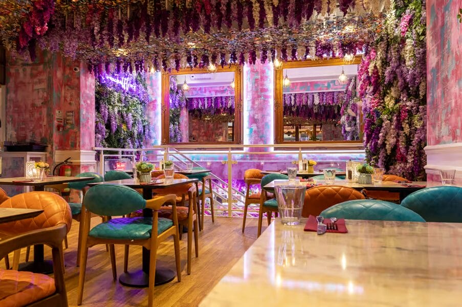 Fleur restaurant with no customers. Floral ceiling, mirrors, and tables and chairs.