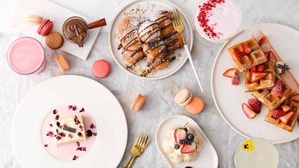A variety of puddings including cakes, macarons, waffles, and pink drinks.