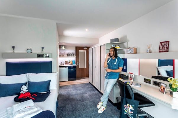 Resident student chatting on his phone in his studio room at Study Inn Brotherton House student accommodation, Leeds.