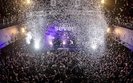 O2 Academy in Leeds busy during a concert, audience with arms in the air and paper falling from the ceiling.