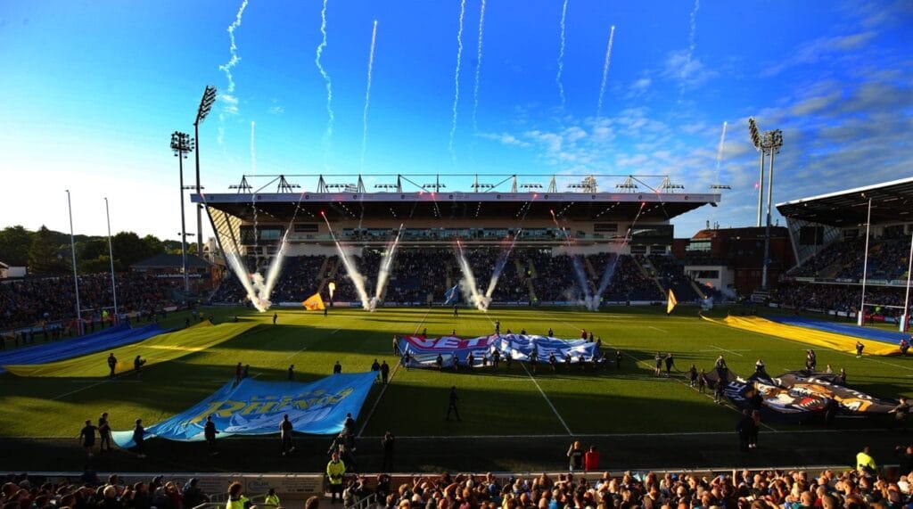 Headlingley Stadium on a summers day, blue skies, full audience, and teams holding their flags and singing the anthems.