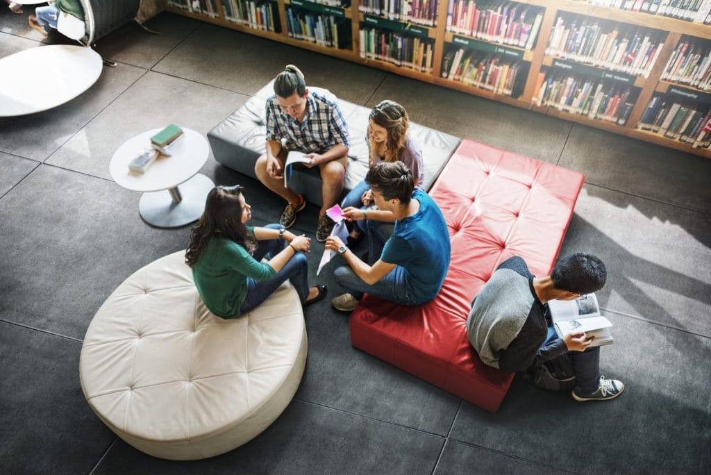 Group of friends relaxing with their laptops in a bright communal area at Exeter student accommodation.