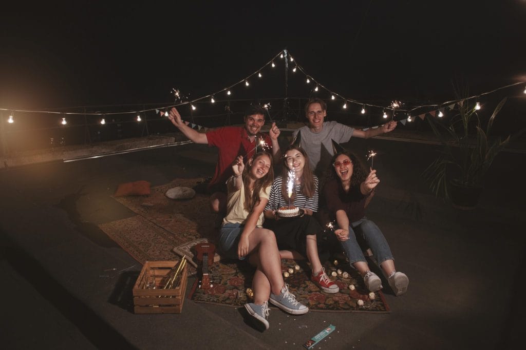 Group of University students enjoying a rooftop gathering under string lights in Loughborough.