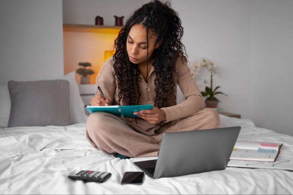 Student sitting on bed managing her finances, symbolising effective budgeting strategies for affordable student living in Bristol