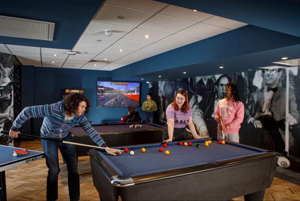 Students enjoying pool and gaming facilities in the vibrant social lounge at Student Accommodation in Leeds at Study Inn