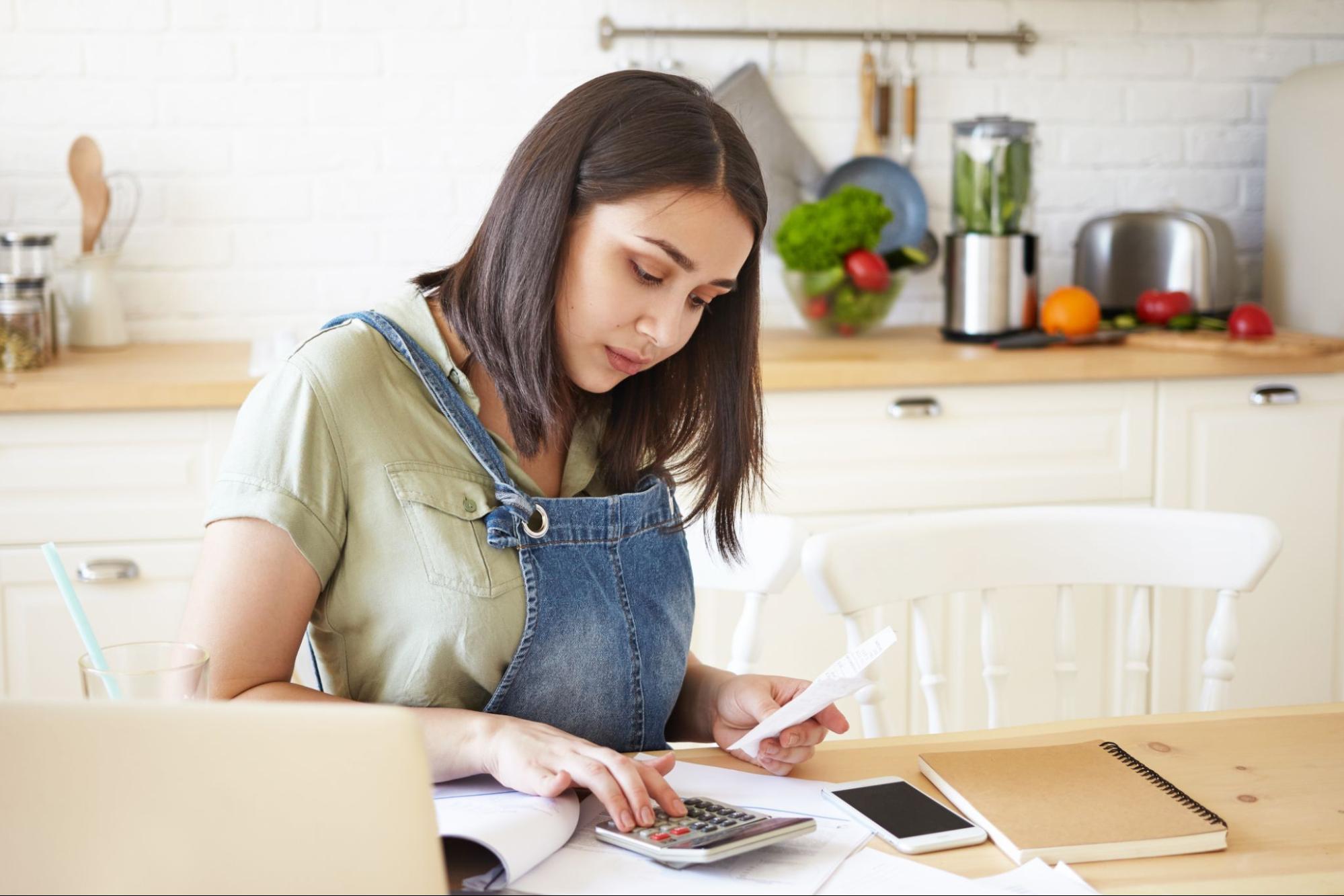 Student budgeting in Leicester accommodation kitchen with calculator and receipts