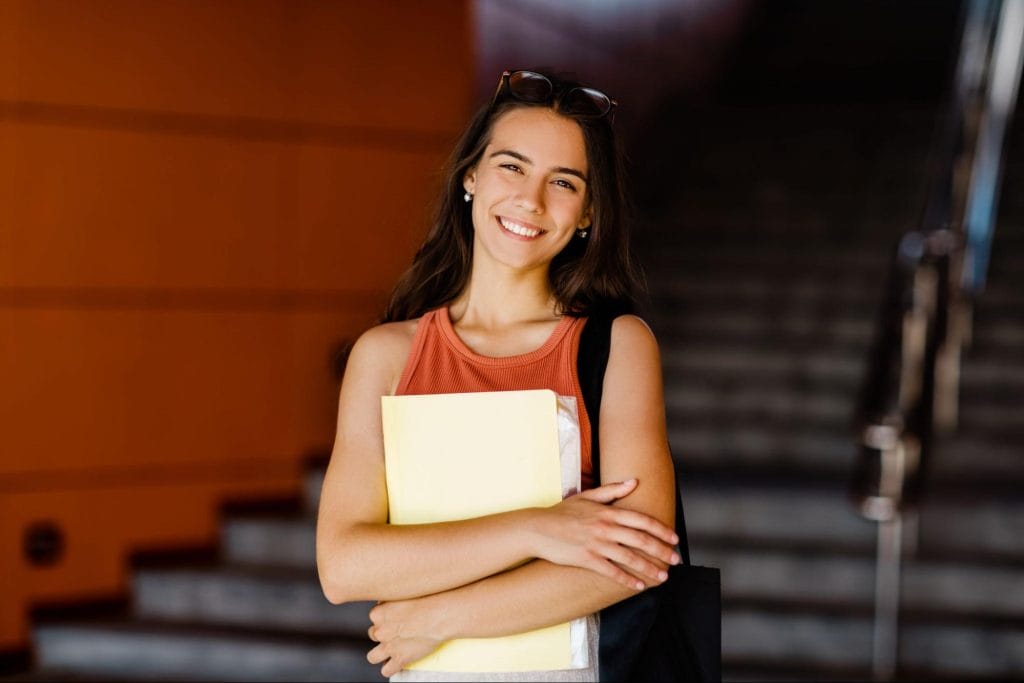 Smiling female student holding folders at luxury student residence in Bristol