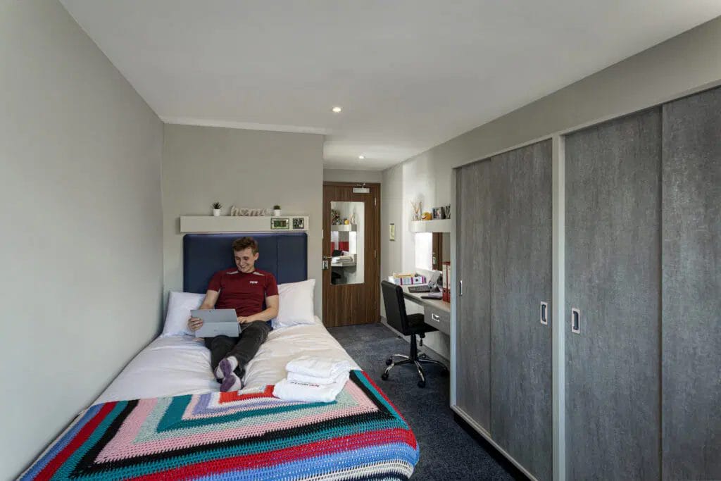Student relaxing in a modern ensuite room at Study Inn student accommodation in Leicester with private study space.